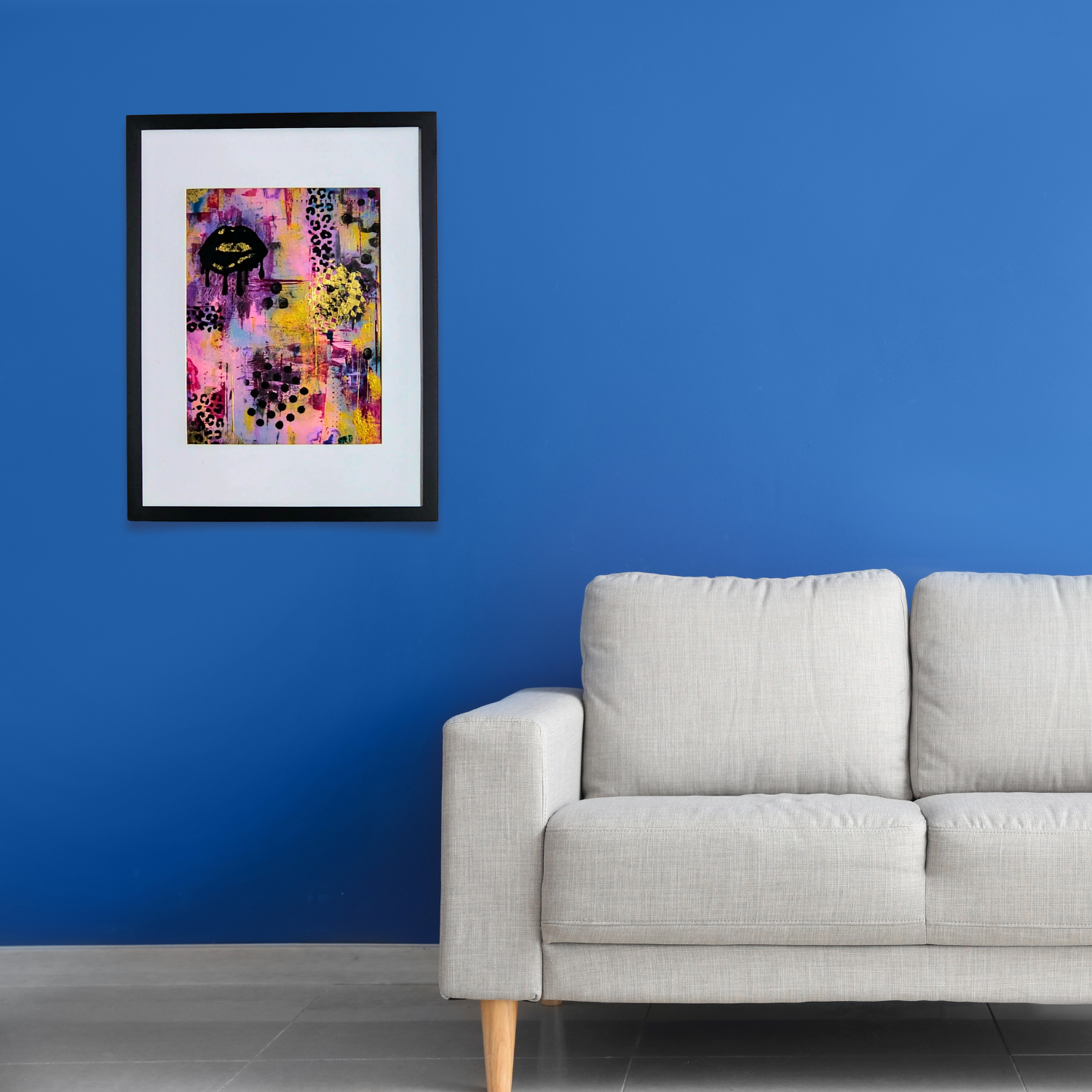 Framed abstract art on a blue wall above a gray sofa