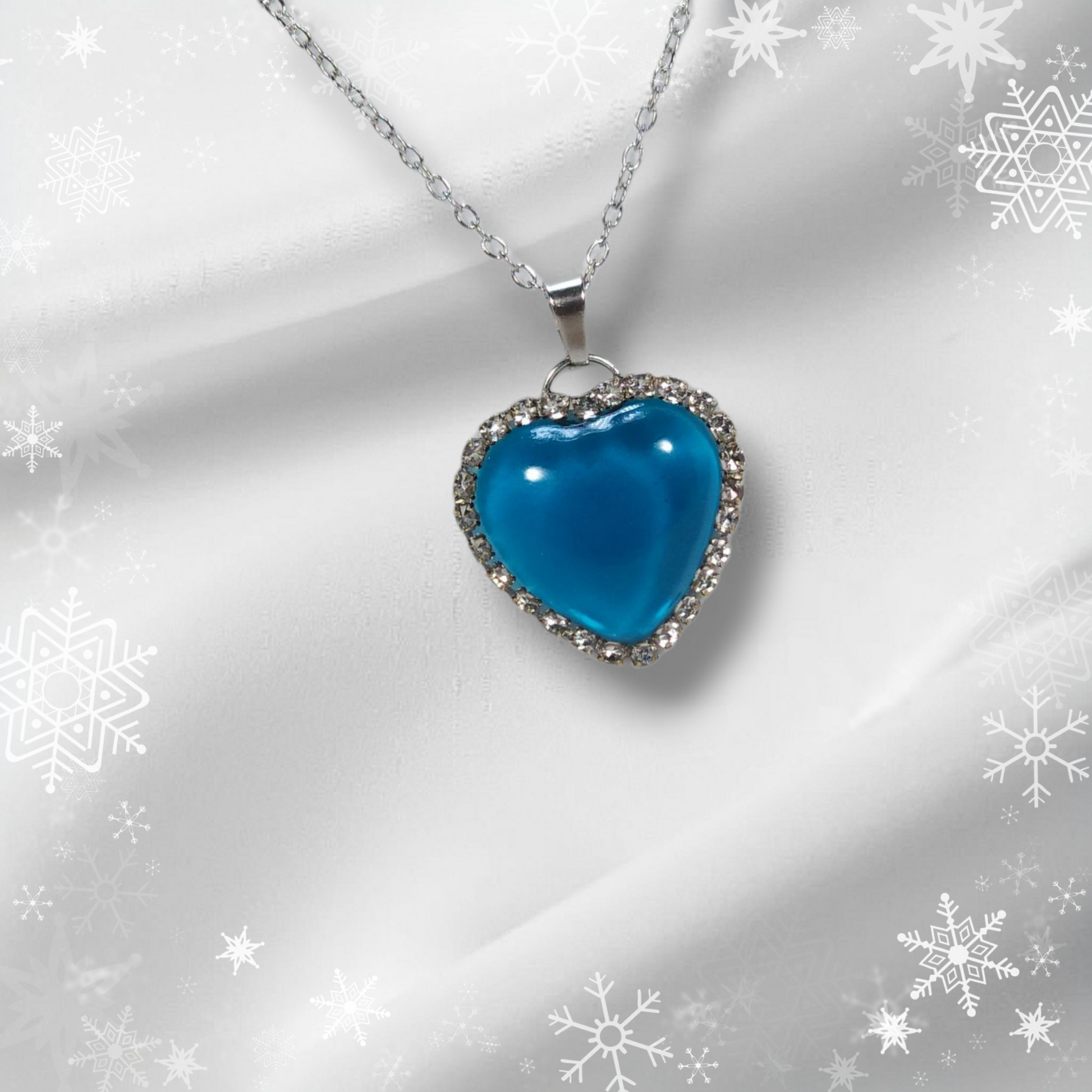 blue resin heart necklace with silver chain and rhinestone border on white background